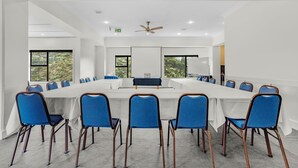 A conference room with a long table, blue chairs, and large windows. - Capital Lodge Motor Inn (Wellington)