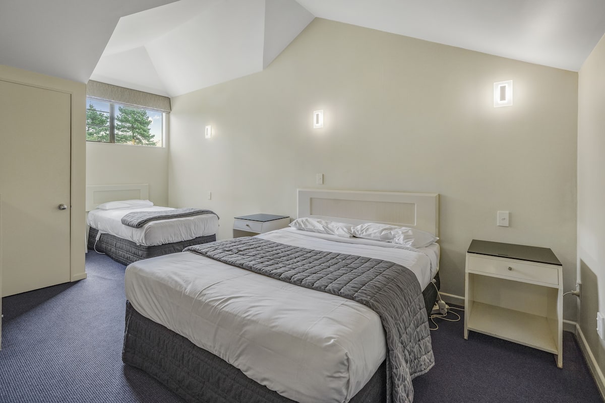 A hotel room with two beds, a desk, and a nightstand.