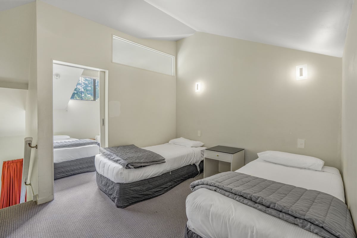 A hotel room with two beds, a nightstand, and a window with a view.