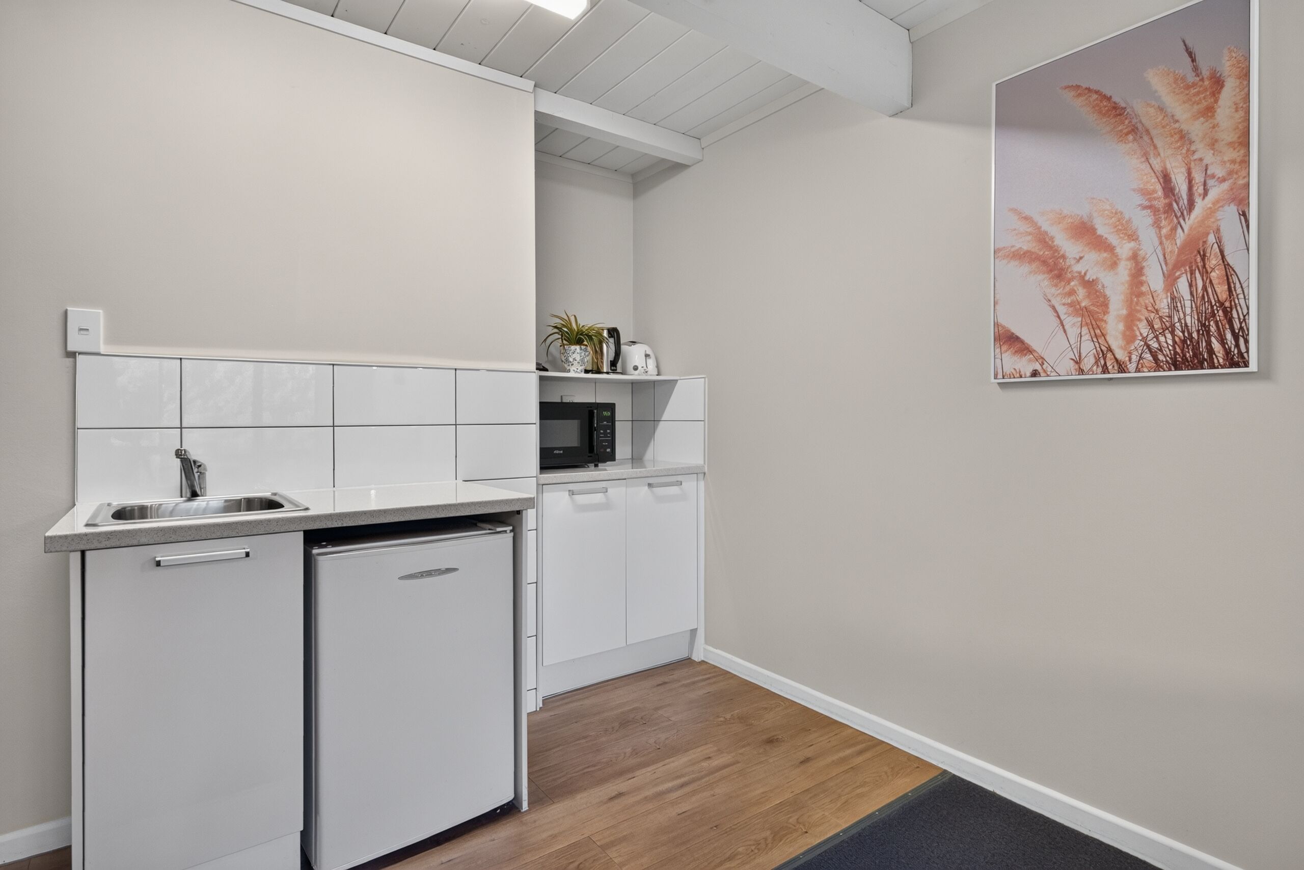 A compact kitchen with white cabinetry, a built-in microwave, and a small refrigerator.
