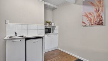 A compact kitchen with white cabinetry, a built-in microwave, and a small refrigerator.