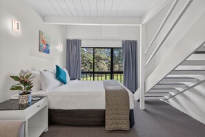 A bedroom with a bed, bedside table, and a window with curtains. - Capital Lodge Motor Inn (Wellington)