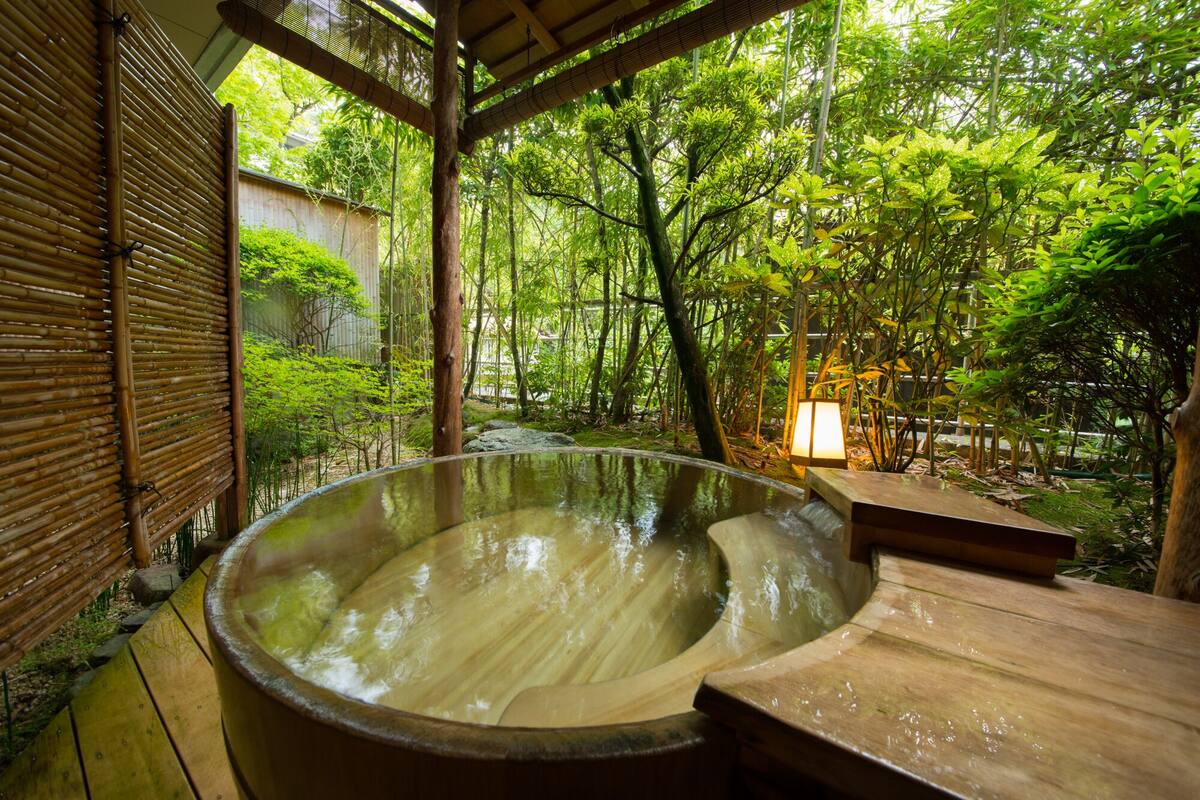 A hot spring bath area with a wooden deck and bamboo structures.