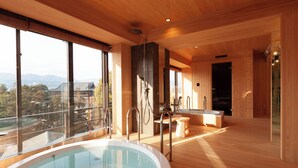 A modern bathroom with a large bathtub, wooden flooring, and a view of the mountains through large windows. - Miyajima Grand Hotel Arimoto (Hatsukaichi)
