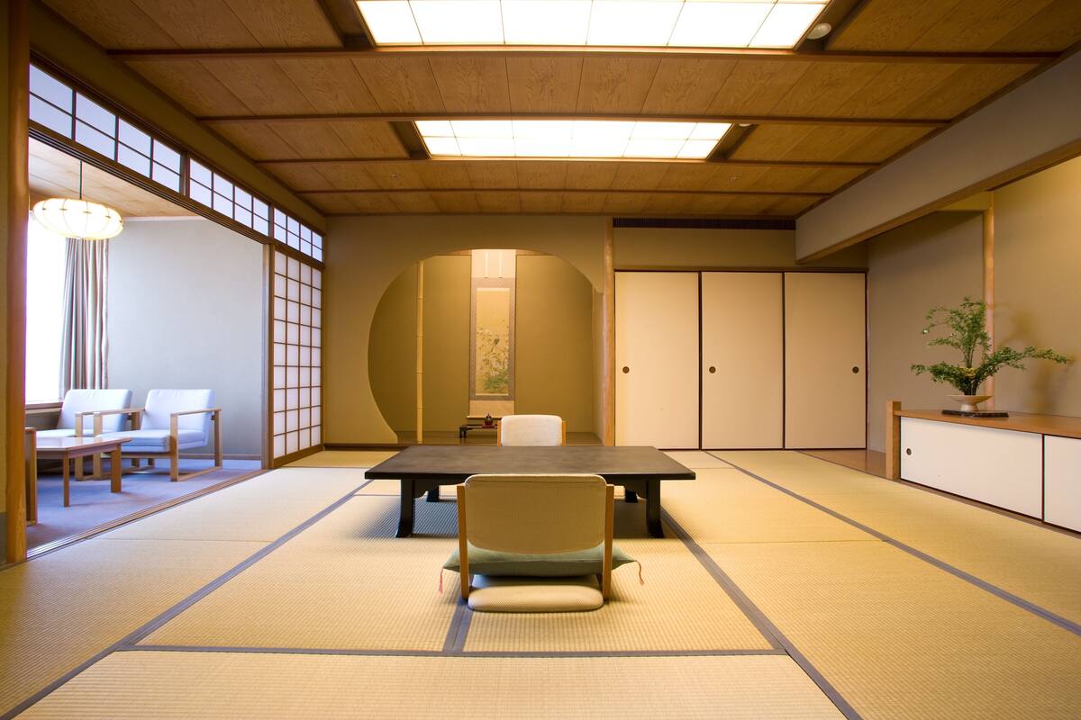 A traditional Japanese room with tatami flooring, a low table, and a chair.