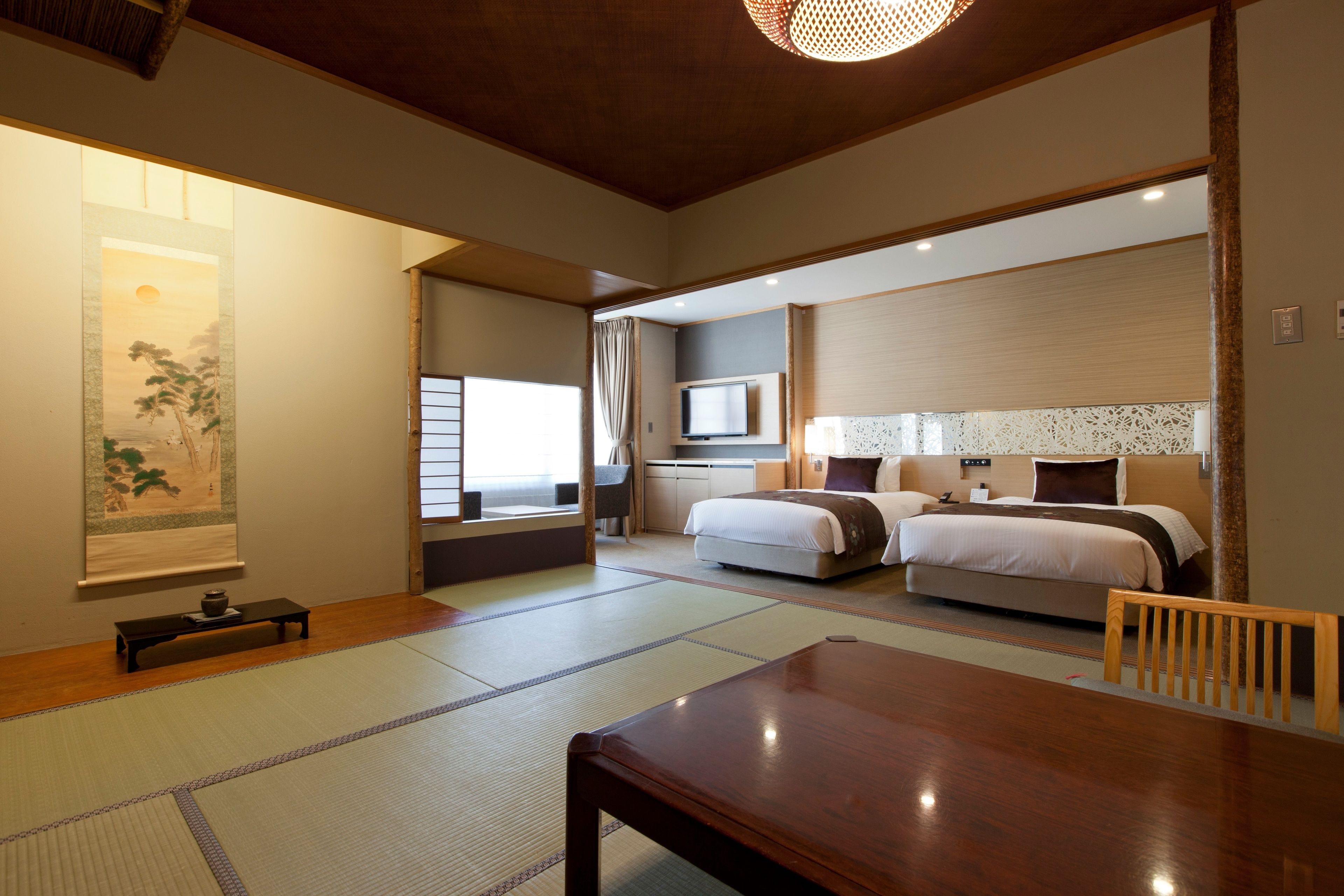 Una habitación de hotel tradicional al estilo japonés, con suelo de tatami, una cama, un escritorio y un televisor.