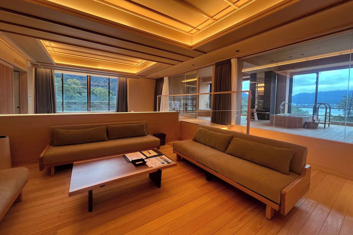 A modern living room with a sofa, a coffee table, and a view of a balcony with a pool.