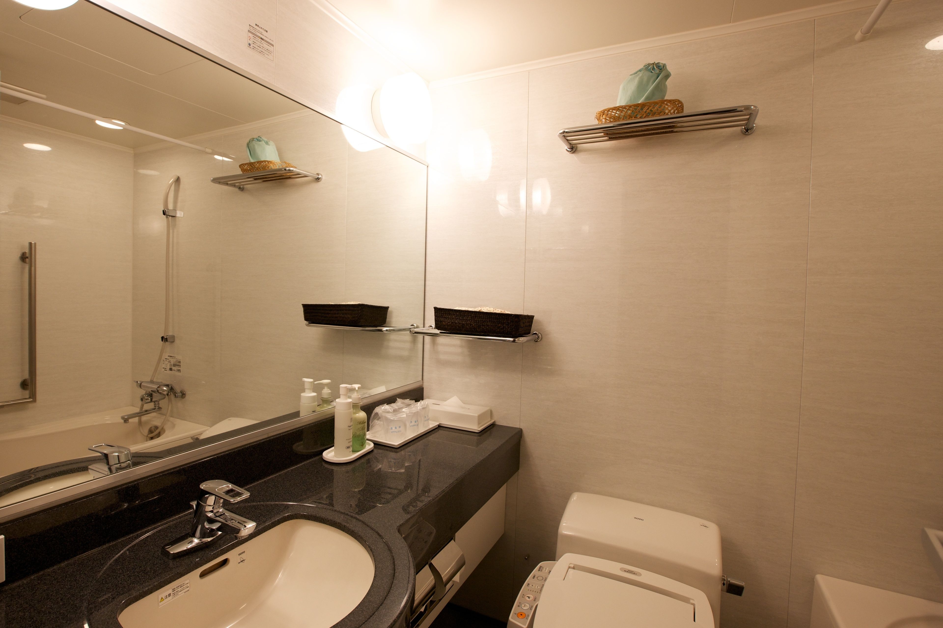 A modern bathroom with a sink, mirror, and toilet.