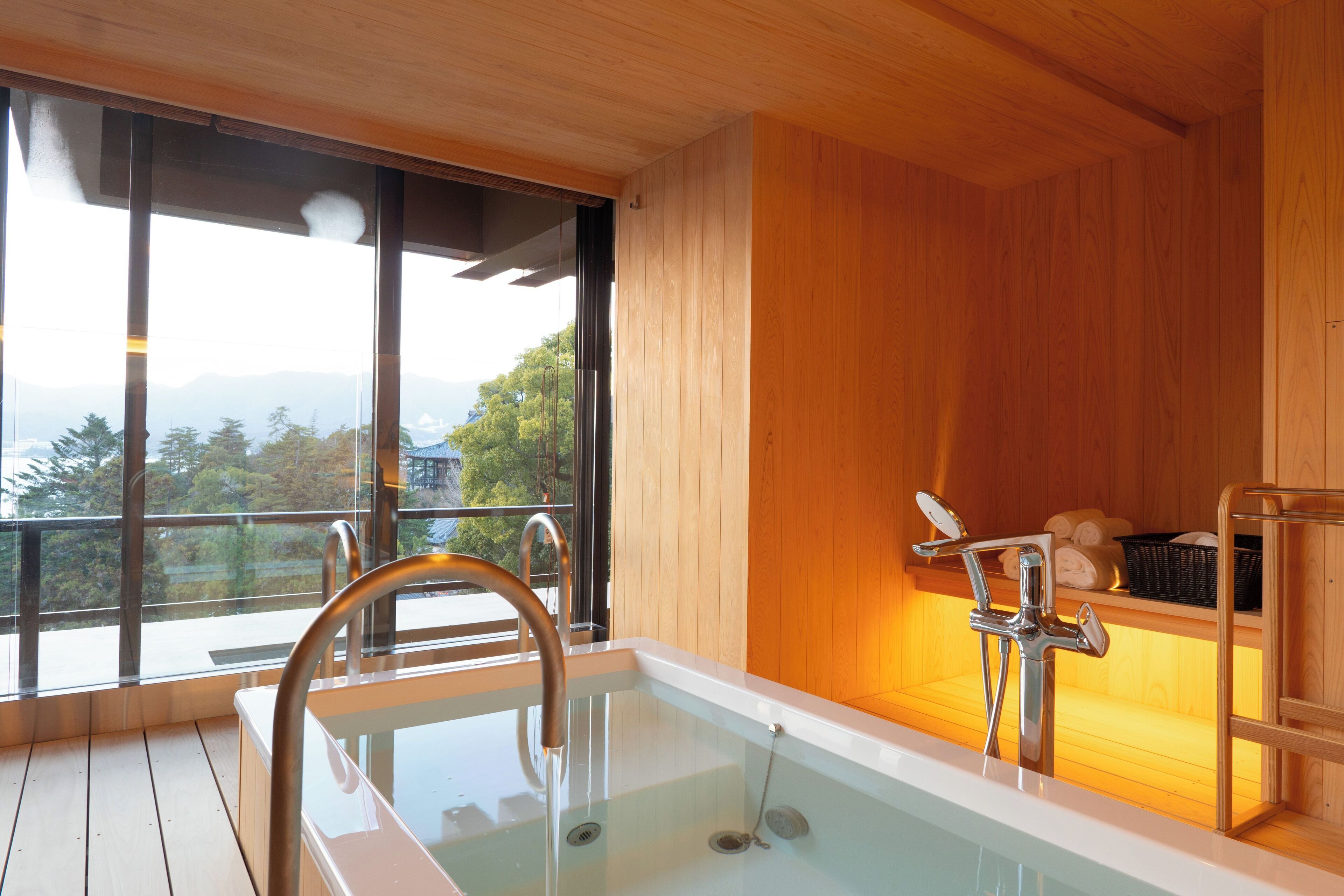 A modern bathroom with a glass-enclosed hot tub, wooden walls, and a view of the outdoors.