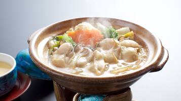A traditional Japanese hot pot with various ingredients, a ceramic bowl, and a blue patterned cup.