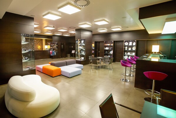 A modern hotel lobby with a seating area, a reception desk, and a display of items.