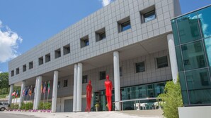 Um edifício moderno com fachada em grade, grandes janelas e uma série de bandeiras na frente.