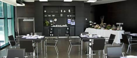 A modern conference room with a dark interior, glass tables, and black chairs.
