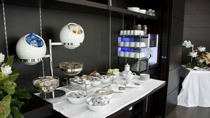 Disposição de buffet com diversos alimentos e utensílios de servir em uma bancada de mármore.