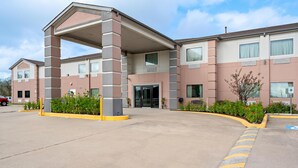 A multi-story hotel with a covered entrance, a parking lot, and a landscaped area with plants. - Americas Best Value Inn Somerville (Somerville)