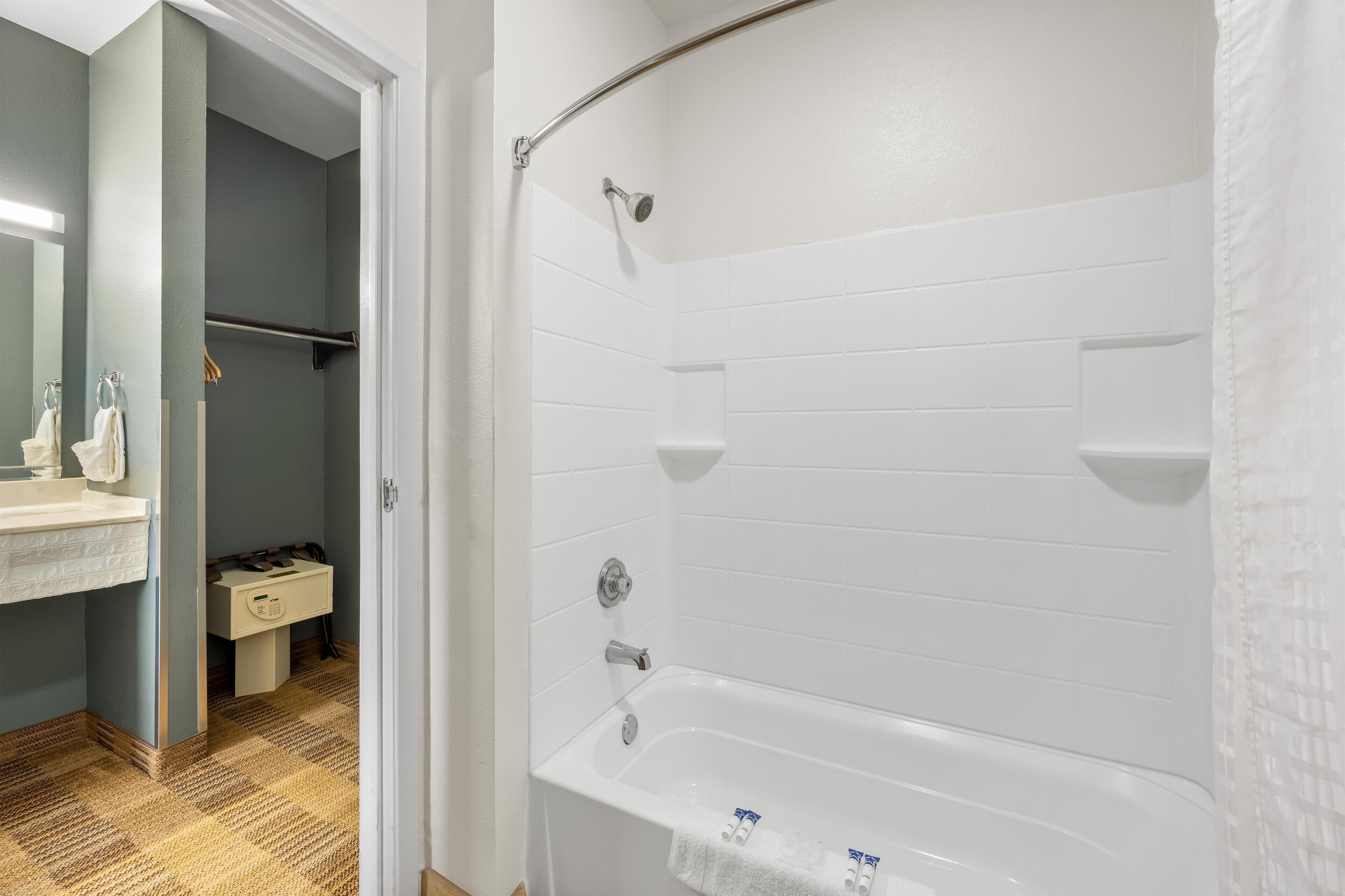 Un bagno con una vasca da bagno bianca, un lavandino con uno specchio e un portascopevoli.