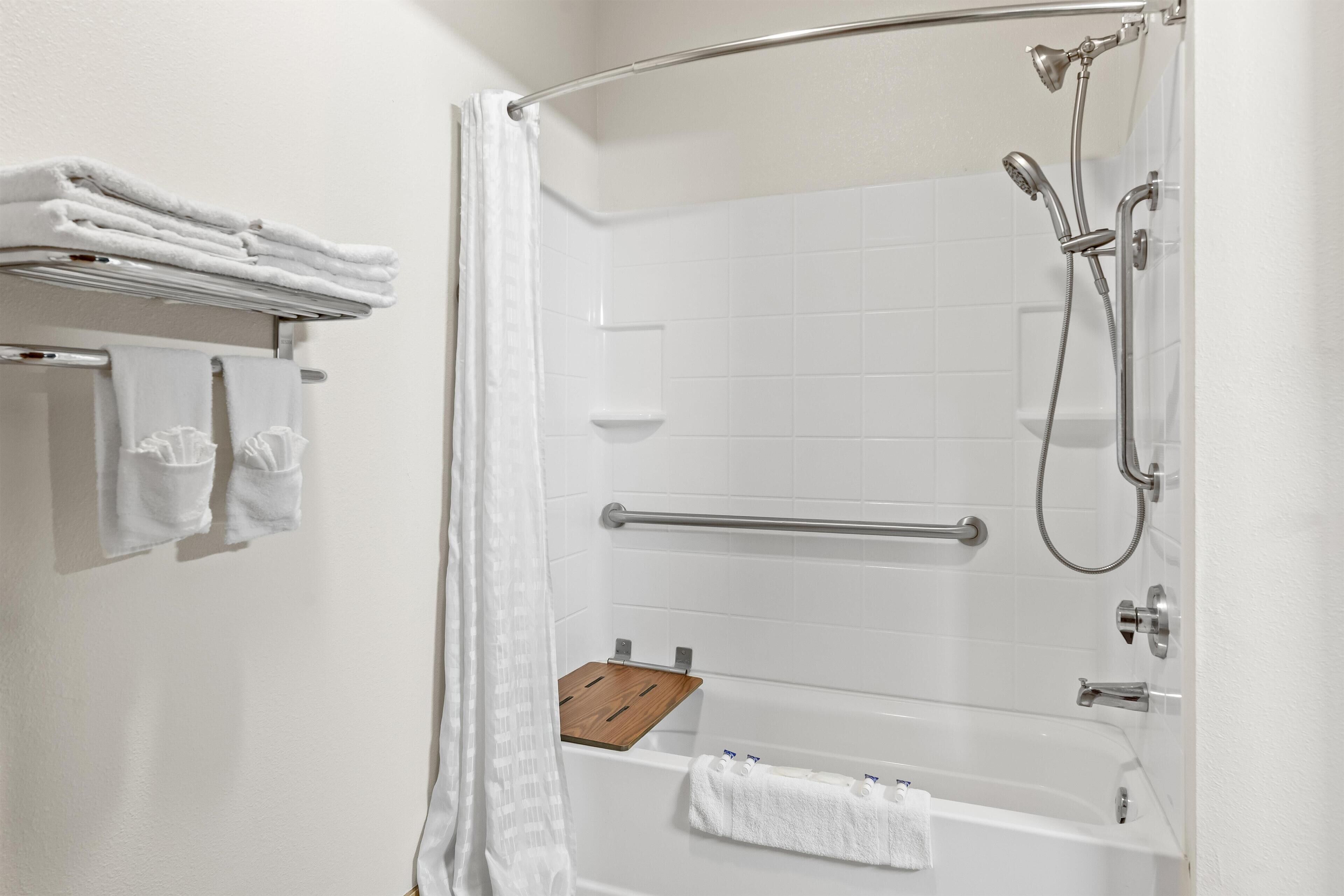 Un baño moderno con ducha a ras de suelo, un estante de madera y toallas ordenadas en un tendedero.