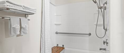 Un baño moderno con ducha a ras de suelo, un estante de madera y toallas ordenadas en un tendedero.
