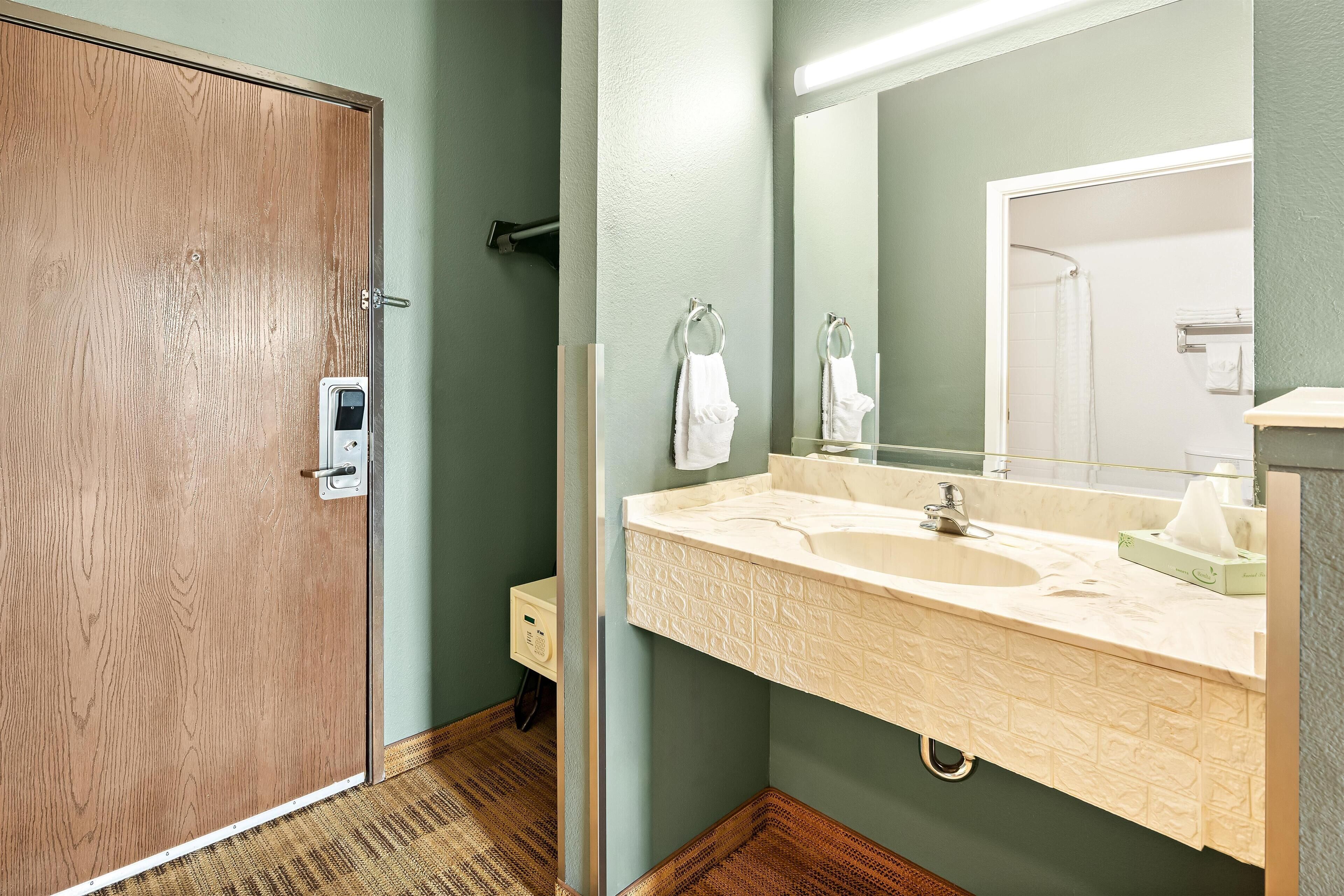 Ein Badezimmer mit Holztür, Waschbecken mit Spiegel und Handtuchhalter.