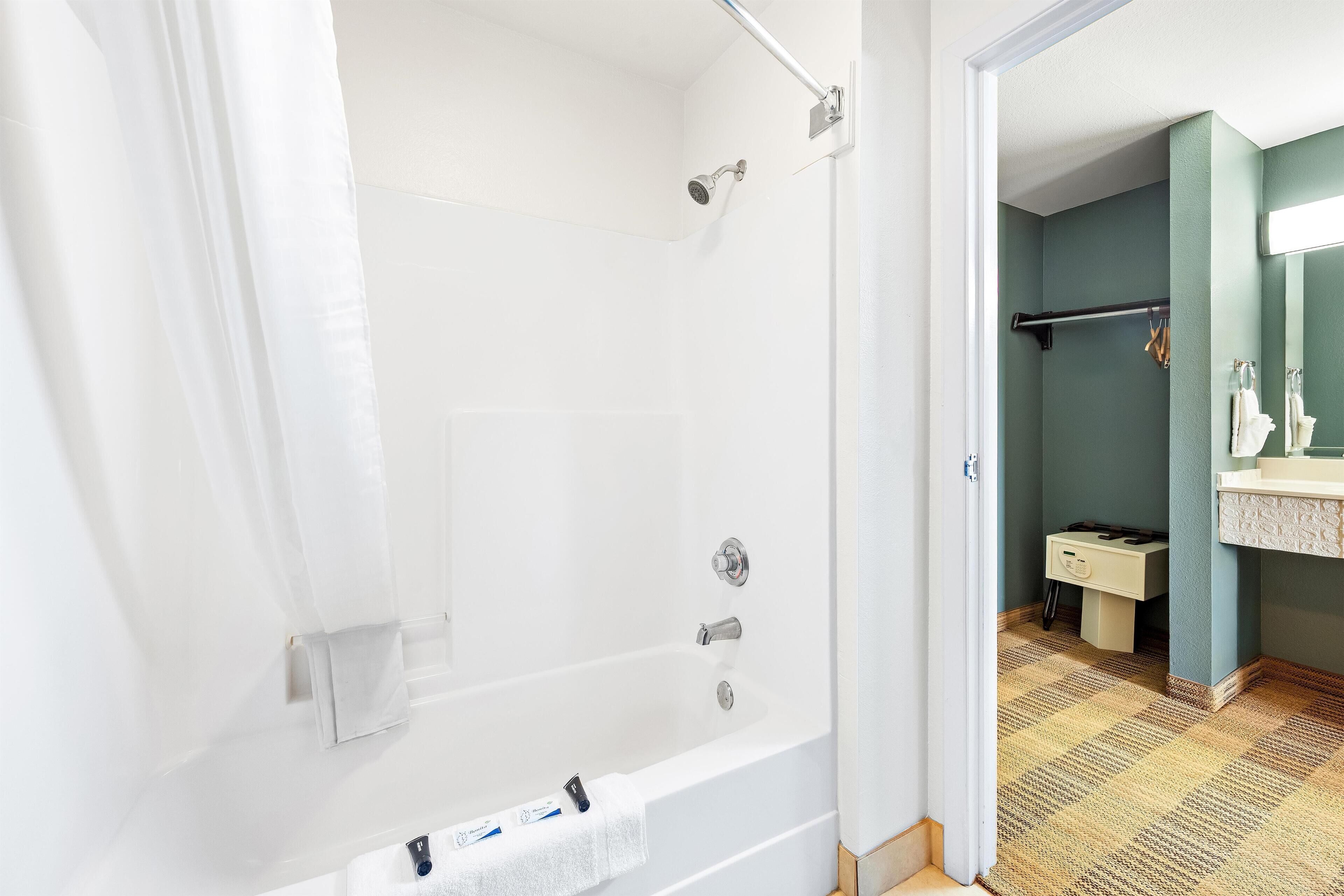 Ein Badezimmer mit einer weißen Badewanne, einer Dusche und einem Waschbecken mit Spiegel.