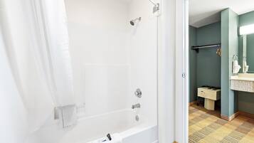 Ein Badezimmer mit einer weißen Badewanne, einer Dusche und einem Waschbecken mit Spiegel.