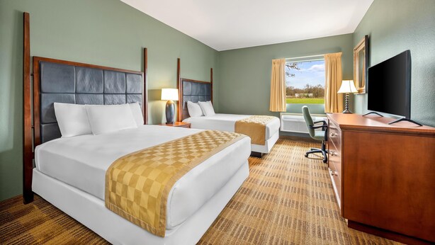 A hotel room with two beds, a desk, a chair, and a TV. - Americas Best Value Inn Somerville (Somerville)