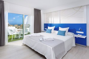 A modern hotel room with a large bed, a balcony with a view of the sea, and a small table with chairs. - Playaolid Suites and Apartments (Adeje)