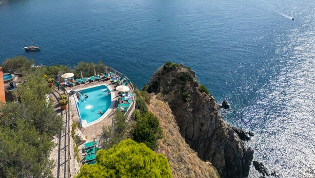 A coastal hotel with a swimming pool, lounge chairs, and a view of the sea. - Punta Chiarito Resort (Forio)