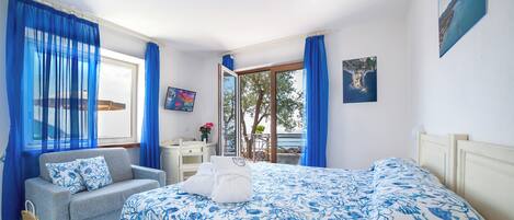 Une chambre à coucher avec un lit, un canapé, une petite table et une fenêtre avec des rideaux.