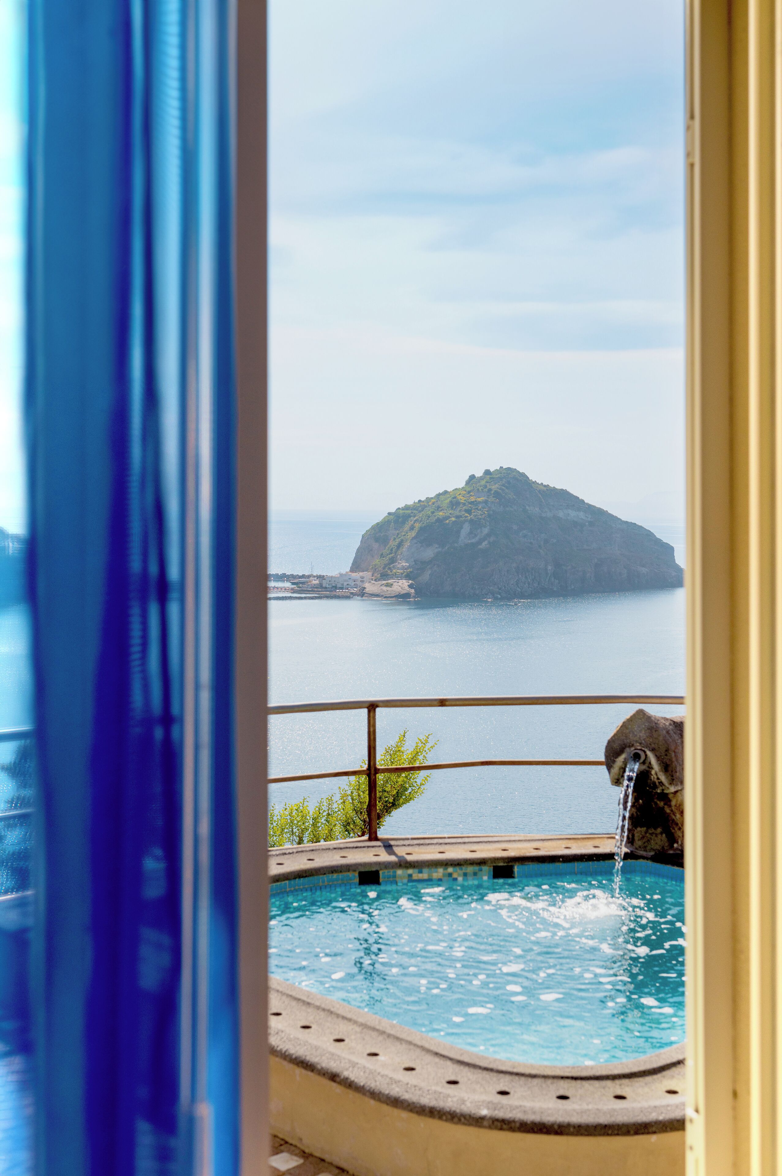 Una piscina con vistas a una isla lejana y una cascada.