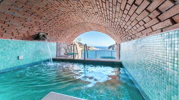 Una piscina interior con agua cristalina y paredes de azulejos, bajo un techo de ladrillo.