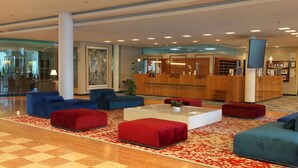 A lobby with a reception desk, seating areas, and a large abstract artwork. - City Hotel Dresden Radebeul (Radebeul)