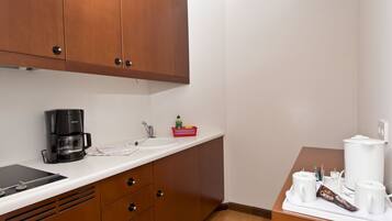 A small kitchenette with a coffee maker, sink, and storage drawers.