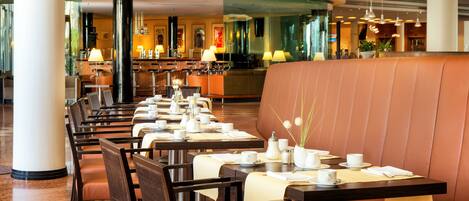 Un ristorante con diversi tavoli e angoli riservati, caratterizzato da tovaglioli bianchi e un arredamento moderno.