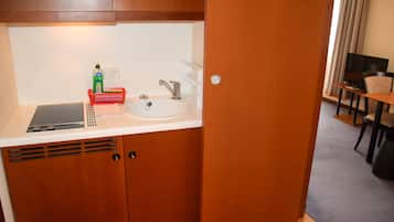 Una kitchenette compacta con un lavamanos, un refrigerador pequeño y un microondas.