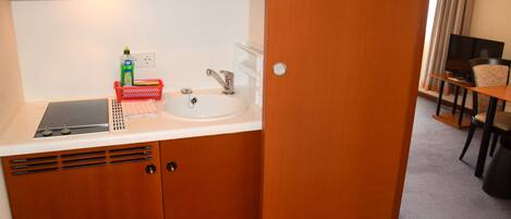A compact kitchenette with a sink, a small refrigerator, and a microwave.