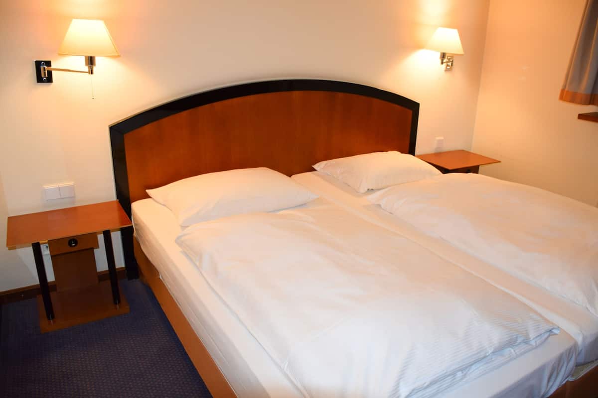 A double bed with a wooden headboard, two bedside tables, and wall-mounted lamps.