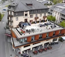 Hotel de varios pisos con terraza en la azotea, que cuenta con asientos al aire libre y sombrillas.