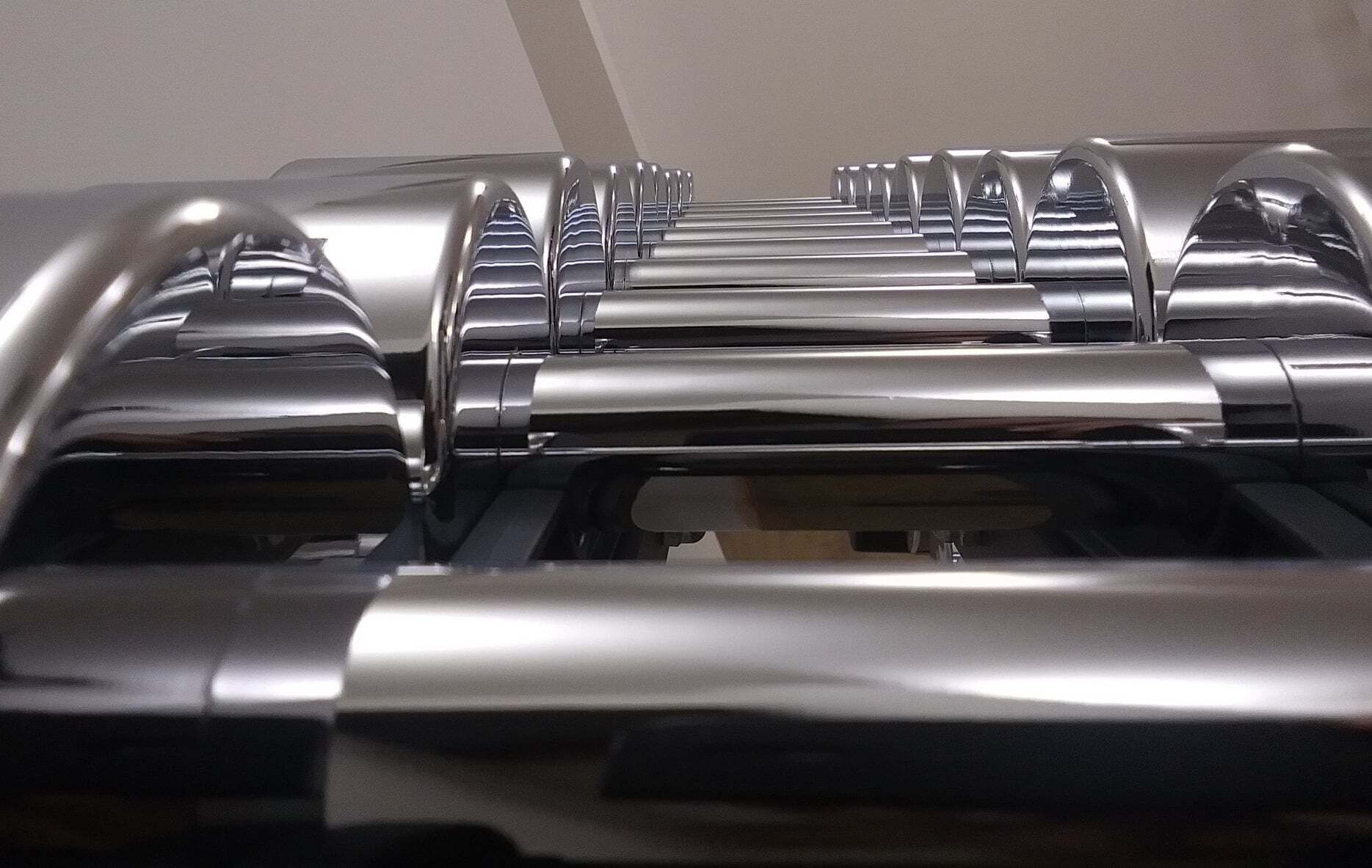 A row of metallic, cylindrical objects with reflective surfaces, likely part of a mechanical or industrial setup.