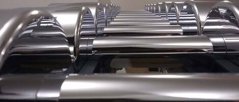 A row of metallic, cylindrical objects with reflective surfaces, likely part of a mechanical or industrial setup.