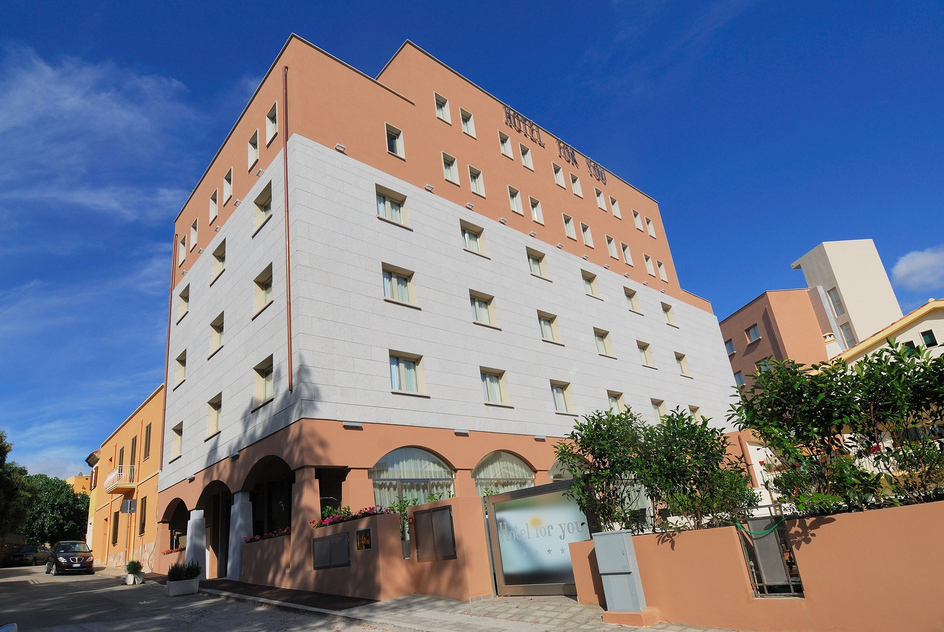Un hotel de diverses plantes amb un disseny arquitectònic modern, que destaca per una entrada prominent amb façana de vidre i un rètol que diu "Hotel for You".