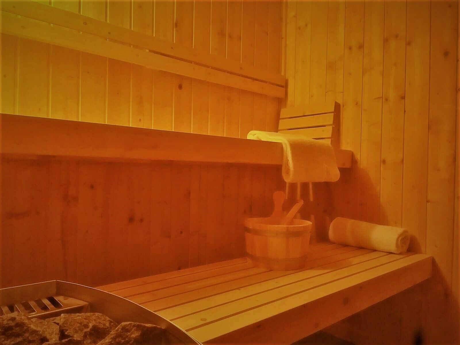 A sauna with wooden benches, a towel rack, and a bucket.
