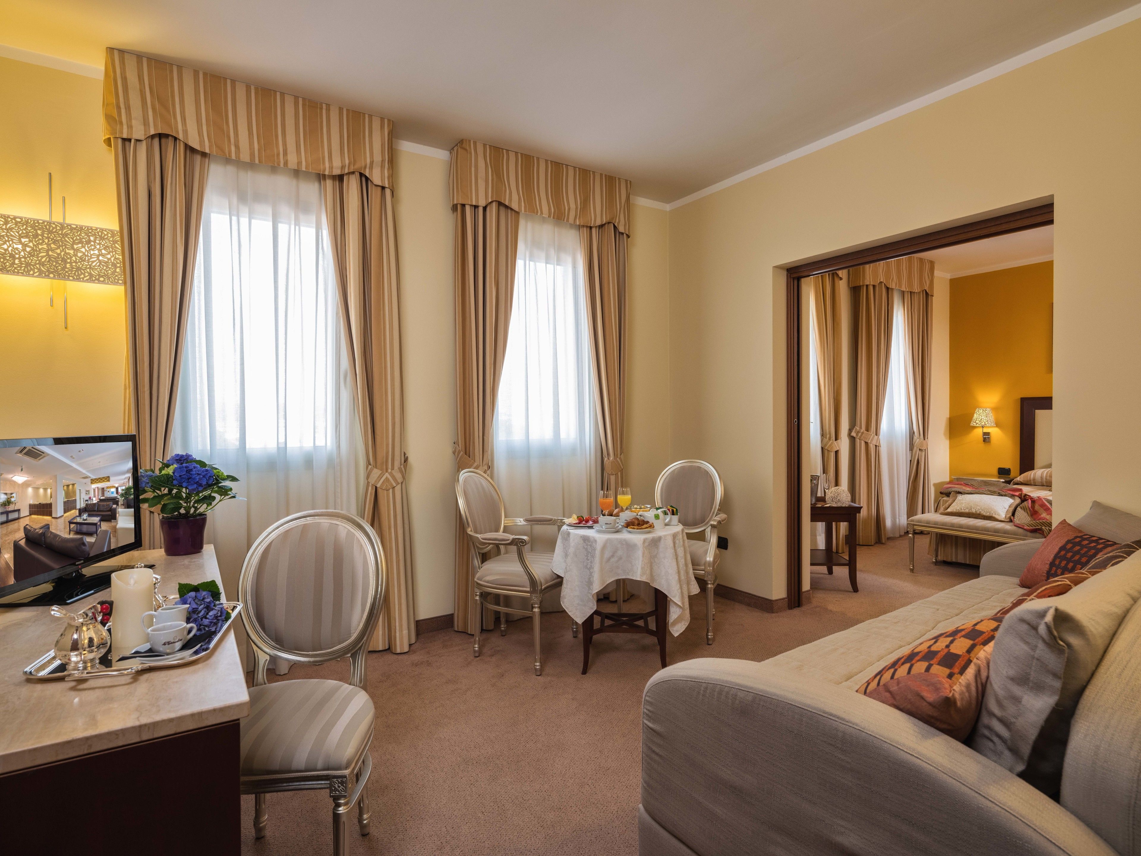 Habitación de hotel con comedor, cama y vista al vestíbulo.