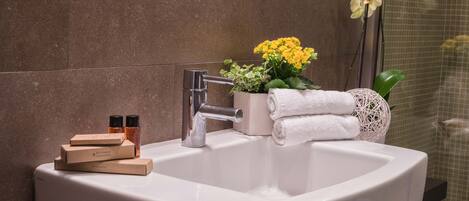 A bathroom with a white sink, a mirror, and a potted plant with yellow flowers.