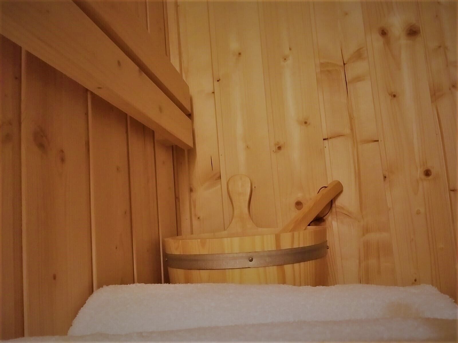 Un sauna en bois, avec un banc en bois et un seau en métal.