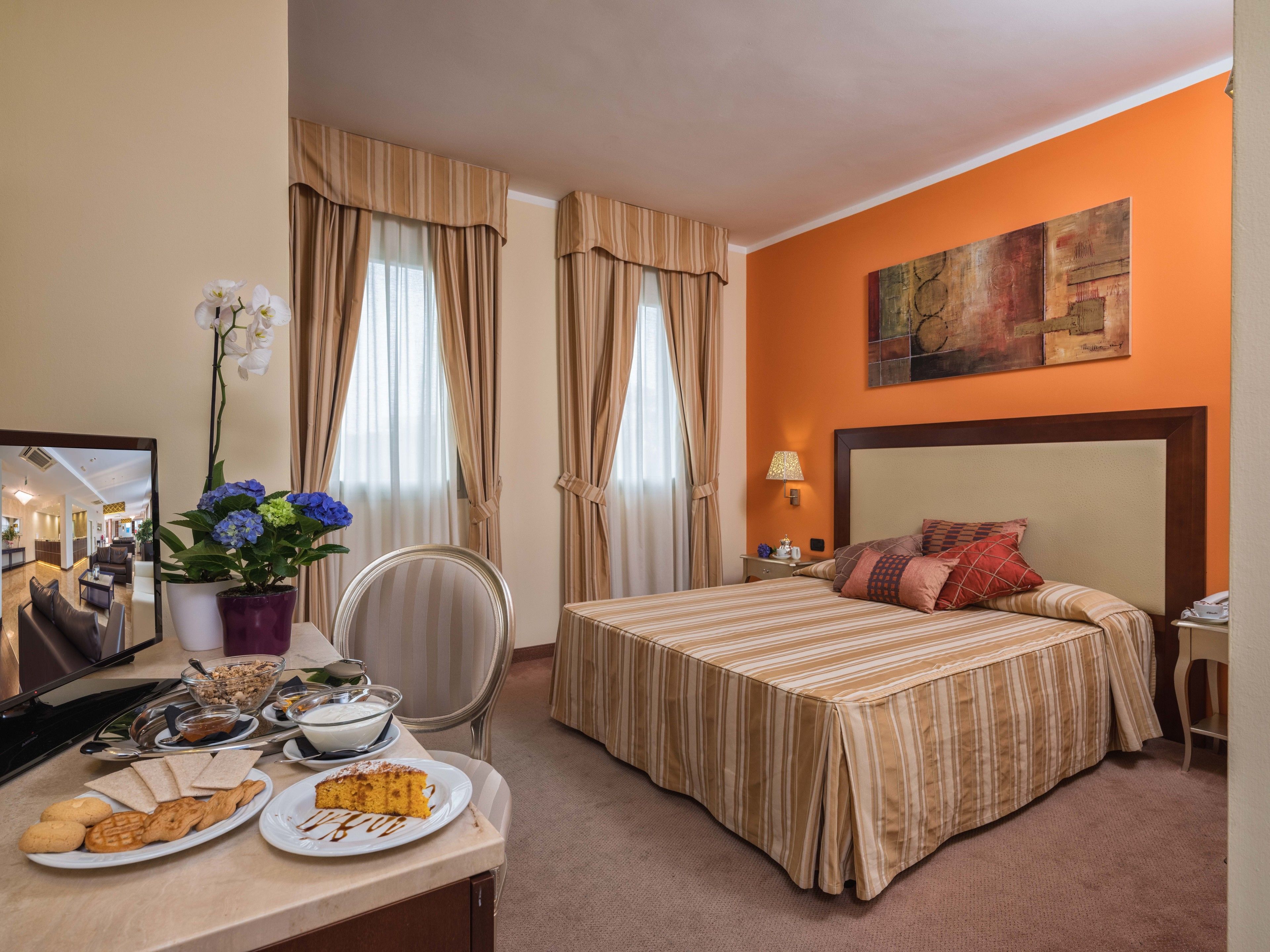 Ein Hotelzimmer mit Bett, einer Essecke mit Frühstück und Blick auf die Hotelhalle.