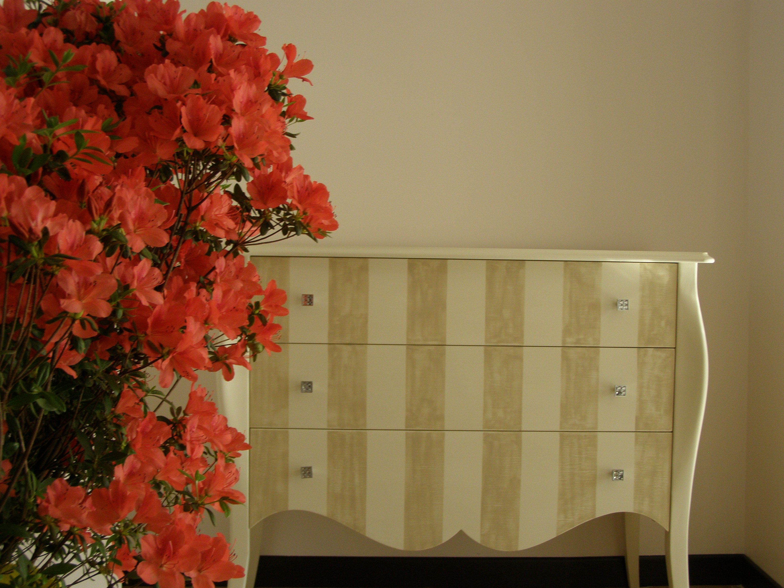 A room with a striped cabinet and a vase of flowers.