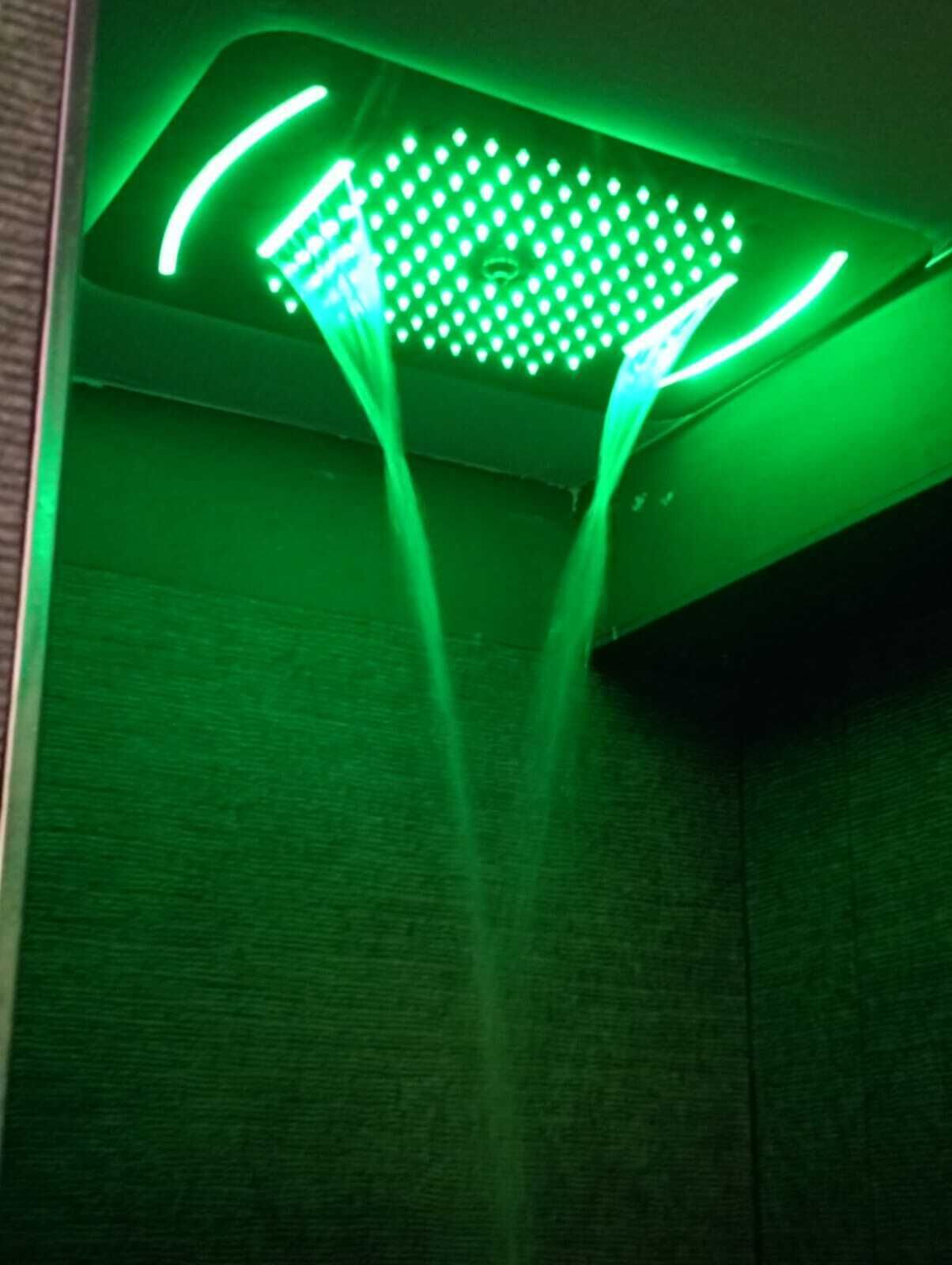 Een douchekop met groene verlichting en meerdere spuitkoppen.