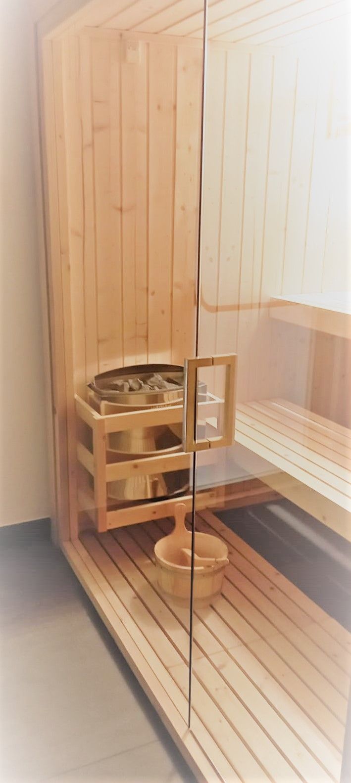 A sauna room with wooden benches and a glass partition.