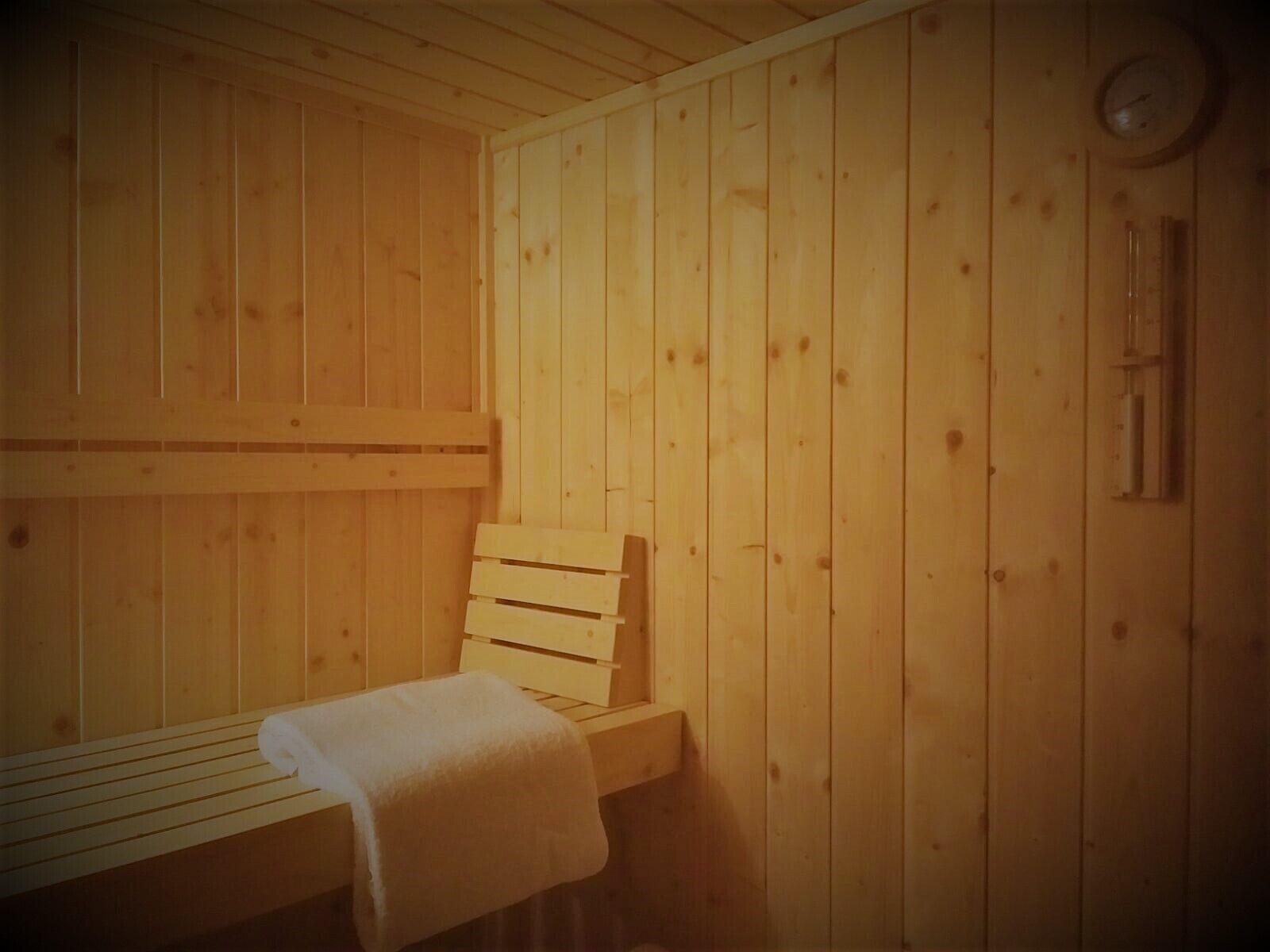 A wooden sauna room with benches and a towel.